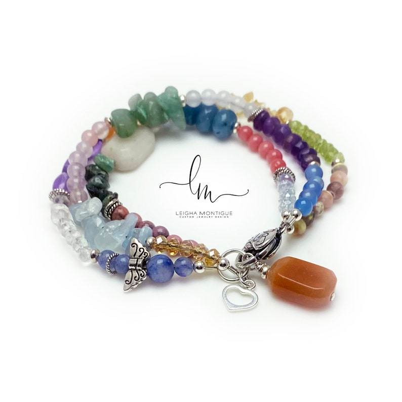 Multi-strand bracelet featuring a variety of colorful gemstones, including amethyst, rose quartz, aquamarine, and citrine. The bracelet has a silver clasp and a heart charm.