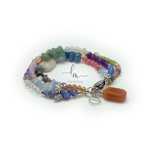 Multi-strand bracelet featuring a variety of colorful gemstones, including amethyst, rose quartz, aquamarine, and citrine. The bracelet has a silver clasp and a heart charm.