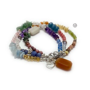 Multi-strand bracelet featuring a variety of colorful gemstones, including amethyst, rose quartz, aquamarine, and citrine. The bracelet has a silver clasp and a heart charm.