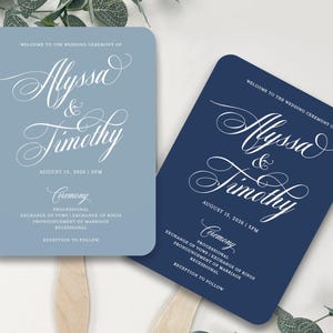 May include: Two rectangular wedding ceremony fans with rounded corners and wooden handles. One fan is light blue and the other is dark navy blue. Both feature white text reading Welcome to the wedding ceremony of Alyssa & Timothy, August 15, 2026.