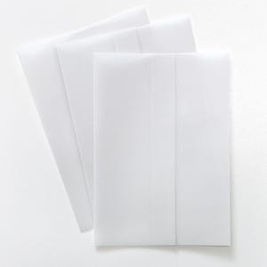 May include: A collection of white paper envelopes arranged on a white surface. The envelopes are rectangular with a folded flap, and are slightly translucent. The image is a top-down view, with the envelopes overlapping each other.