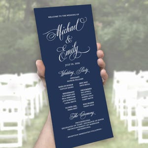 May include: A tall, rectangular navy blue wedding program card with white text. The header reads Welcome to the Wedding of Michael & Emily, July 25, 2026. It lists the wedding party members and the ceremony order, including processional and recessional.