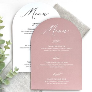 May include: Two arched menu cards with white and dusty rose backgrounds. The text includes headings for Menu, starter, entree, and dessert, followed by food items like Italian Bruschetta, Filet of Grilled Salmon, and Italian Almond Cake in black and white.