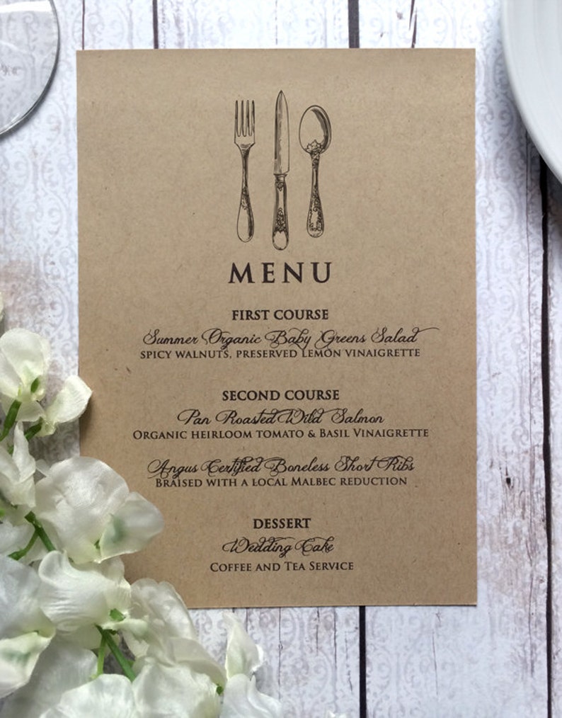 Op de afbeelding: Een bruine papieren menukaart met een vintage bestekillustratie en een lijst met gerechten voor een huwelijksreceptie. Het menu bevat Zomersalade met biologische babygroenten, Gebakken Wilde Zalm, Angus Certified Boneless Short Ribs, Trouwtaart en koffie- en theeservice.