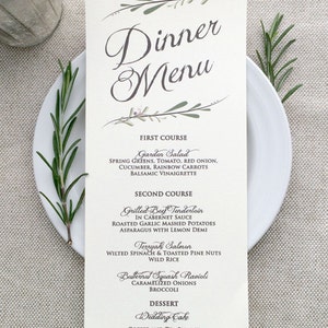 May include: A wedding dinner menu with a floral design. The menu includes a garden salad, grilled beef tenderloin, teriyaki salmon, butternut squash ravioli, wedding cake, coffee and tea service, and a dessert display.