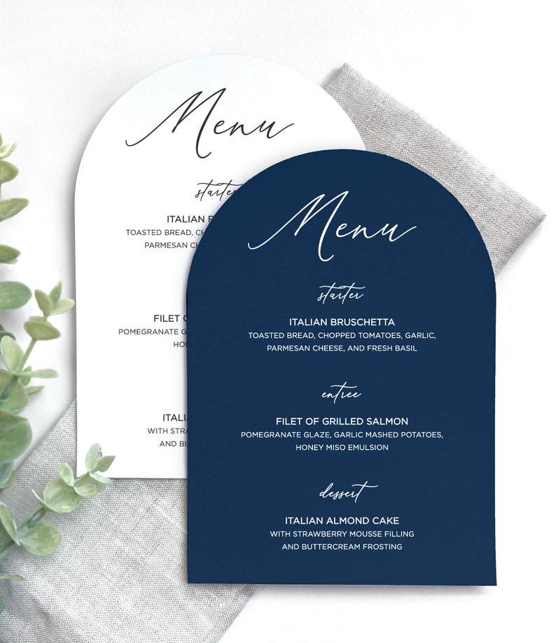 May include: Two arched menu cards, one white and one navy blue, featuring elegant script headings for Menu, starter, entree, and dessert. The text lists Italian Bruschetta, Filet of Grilled Salmon, and Italian Almond Cake with detailed descriptions.