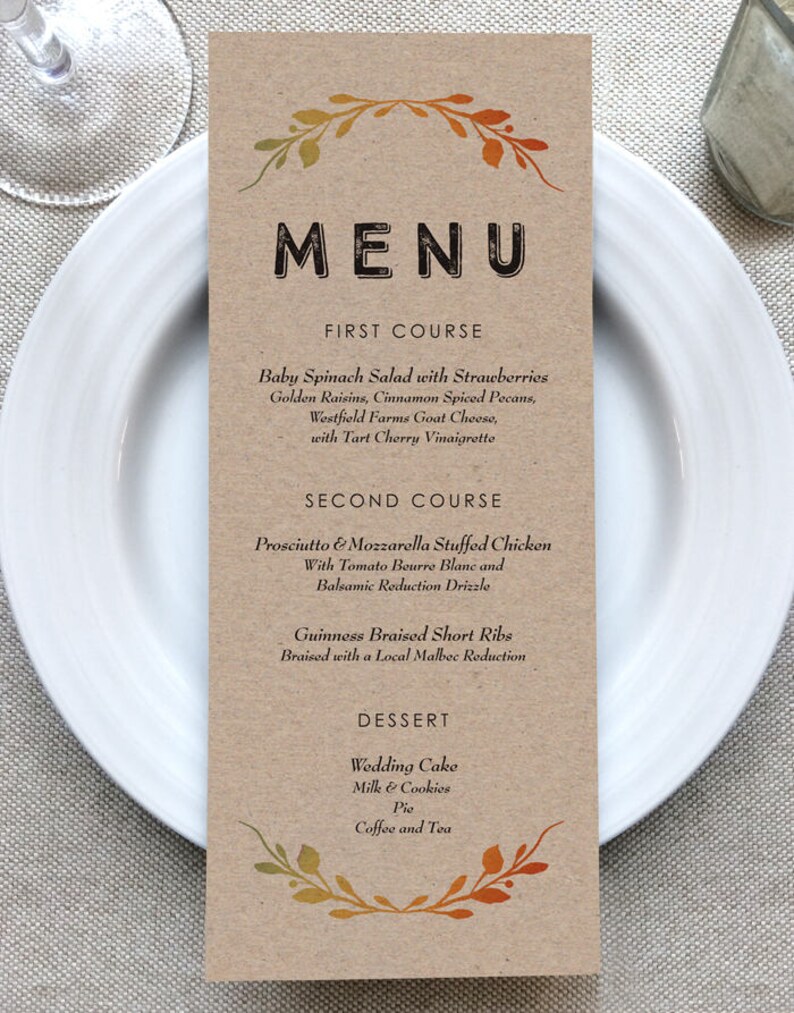 May include: A brown paper menu with a fall-themed border. The menu lists the courses for a meal: First Course: Baby Spinach Salad with Strawberries, Golden Raisins, Cinnamon Spiced Pecans, Westfield Farms Goat Cheese, with Tart Cherry Vinaigrette. Second Course: Prosciutto & Mozzarella Stuffed Chicken with Tomato Beurre Blanc and Balsamic Reduction Drizzle. Guinness Braised Short Ribs Braised with a Local Malbec Reduction. Dessert: Wedding Cake, Milk & Cookies, Pie, Coffee and Tea.