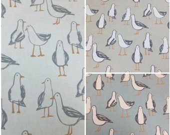 May include: A light blue fabric with a repeating pattern of white seagulls. The seagulls are drawn in a simple, stylized manner and have a light brown beak and feet.