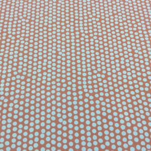 Può includere: Un tessuto color pesca con un motivo a pois bianchi. I pois sono disposti in diagonale.
