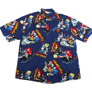 May include: A short-sleeved button-down shirt with a navy blue background and a colorful graphic print. The print features various figures in action poses with red, yellow, blue, and white accents. The shirt has a classic collar and button closure.