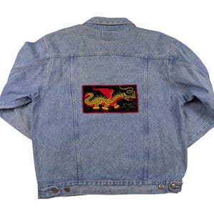 May include: A light blue denim jacket with a red, yellow, and green embroidered dragon patch on the back.