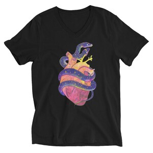 Op de afbeelding: Zwart V-hals T-shirt met een kleurrijke illustratie van een menselijk hart omwikkeld door een sterrenslang. Het hart is roze en geel, en de slang is paars met gele sterren. Het ontwerp is gecentreerd op de borst.