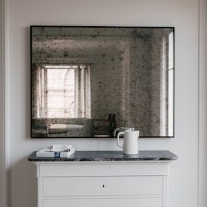 Steel framed wall mirror. Antiqued mirror. Distressed antiqued mirror with subtle black frame. Decorative mirror w/ handmade antique glass