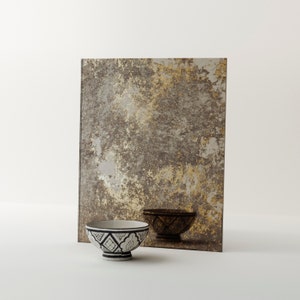 May include: A square, antique-looking mirror with a distressed, gold and brown finish. The mirror is reflecting a white bowl with a black and white geometric pattern.