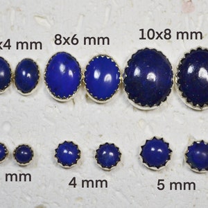 Peut inclure: Un ensemble de 10 paires de boucles d'oreilles en argent avec des pierres de lapis-lazuli bleues. Les pierres sont disponibles en différentes tailles, allant de 3 mm à 10 mm. Les boucles d'oreilles sont présentées sur une surface blanche.