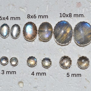 Puede incluir: Surtido de cabujones redondos de labradorita en varios tamaños, que van desde 3 mm hasta 10x8 mm. Las piedras están engastadas en biseles de plata y tienen un brillo iridiscente.