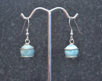 May include: A pair of silver earrings with blue and white iridescent gemstone balls wrapped in silver wire.