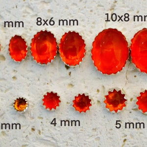 May include: Assortment of orange glass cabochons in various sizes, ranging from 3 mm to 10x8 mm. The cabochons are set in silver bezels with a scalloped edge.