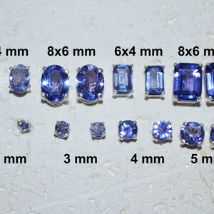Pode incluir: Um conjunto de dez pedras preciosas de safira azul de vários tamanhos, variando de 2 mm a 8 mm. As pedras preciosas são exibidas em uma superfície branca com suas medidas rotuladas em milímetros.
