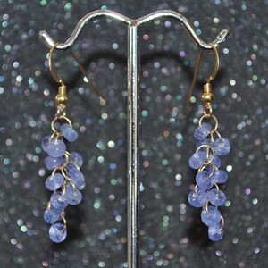 May include: A pair of gold dangle earrings with a cluster of light blue gemstone beads.