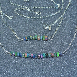 May include: Two silver chains with a row of iridescent black opal beads on each. The chains are layered on top of each other and the beads are evenly spaced.