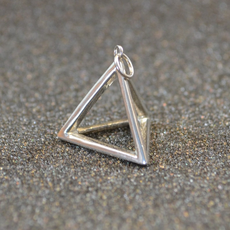 Puede incluir: Un dije de plata en forma de pir&aacute;mide con un bucle en la parte superior para sujetarlo a un collar o pulsera.