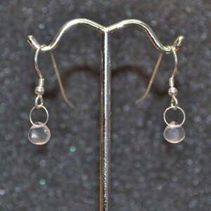 May include: A pair of silver earrings with pink gemstone drops.