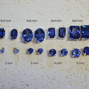Könnte beinhalten: Eine Sammlung blauer Edelstein-Ohrstecker in verschiedenen Größen und Formen, darunter oval, rechteckig und rund. Die Größen reichen von 2 mm bis 8x6 mm. Die Ohrringe sind in silberfarbenem Metall gefasst.
