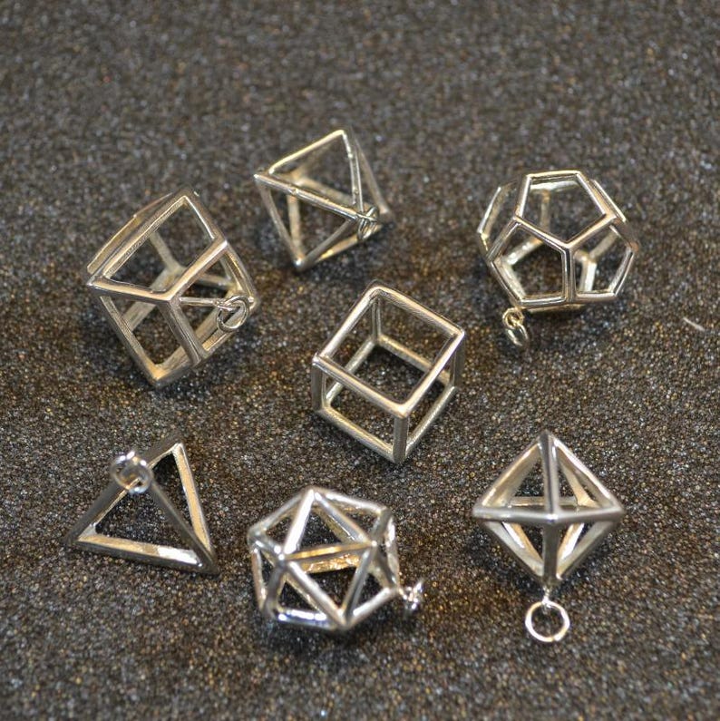 Puede incluir: Un conjunto de nueve colgantes geom&eacute;tricos de plata, que incluyen un cubo, una pir&aacute;mide y otras formas. Los colgantes est&aacute;n hechos de alambre y tienen un aspecto delicado y aireado.