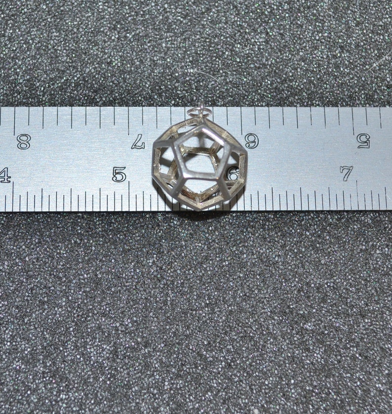 Peut inclure: Un pendentif g&eacute;om&eacute;trique en argent en forme de dod&eacute;ca&egrave;dre, mesur&eacute; &agrave; l'aide d'une r&egrave;gle.