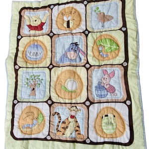 Pode incluir: Um cobertor de bebê com tema do Winnie the Pooh com um design de patchwork. O cobertor apresenta vários personagens das histórias do Winnie the Pooh, incluindo o Winnie the Pooh, Tigger, Piglet e Eeyore. O cobertor é feito de tecido macio e confortável e é perfeito para o quarto de um bebê.