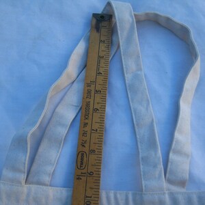 May include: A cream-colored canvas tote bag with matching straps. A wooden ruler, marked in inches, is placed vertically against the bag, showing measurements. The ruler is marked with the text "18 DRITZ YARDSTICK No. 742 75f SCOVILL".