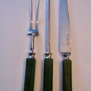 May include: A set of three vintage kitchen knives with green plastic handles. The knives include a carving knife, a steak knife, and a fork.