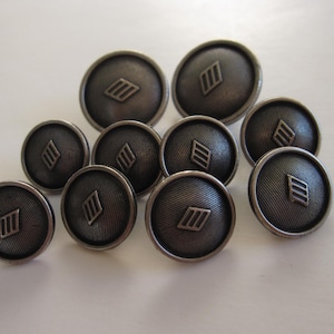 May include: A group of ten silver-toned buttons with a geometric design. The buttons are round and have a raised design of three parallel lines.