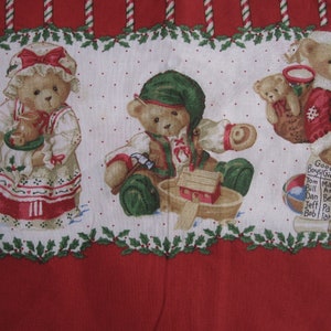 Könnte beinhalten: Ein weißer Stoff mit rotem Rand und einem sich wiederholenden Muster aus Teddybären. Die Bären sind in verschiedenen Outfits gekleidet, darunter ein rot-weißes Weihnachtsmannkostüm, ein grünes Elfenkostüm und ein weißes Kleid mit einer roten Schleife. Der Stoff zeigt auch Stechpalmenblätter und -beeren, Zuckerstangen und eine Namensliste für "Good Boys and Girls".