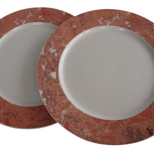 May include: Two round ceramic dinner plates with a white center and a red and white marbled rim.