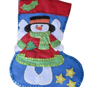 Könnte beinhalten: Blauer Weihnachtsstrumpf mit einer Schneemann-Applikation. Der Schneemann trägt ein rot-grünes Outfit mit einem grünen Schal und einem weißen Hut. Der Strumpf ist mit blauen und goldenen Pailletten verziert.