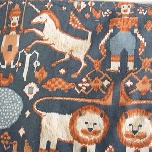 以下が含まれることがあります： ライオン、馬、鳥、そして様式化された人間の図形が繰り返されるパターンが施された青い布。パターンは茶色、白、青の色合いで構成されています。