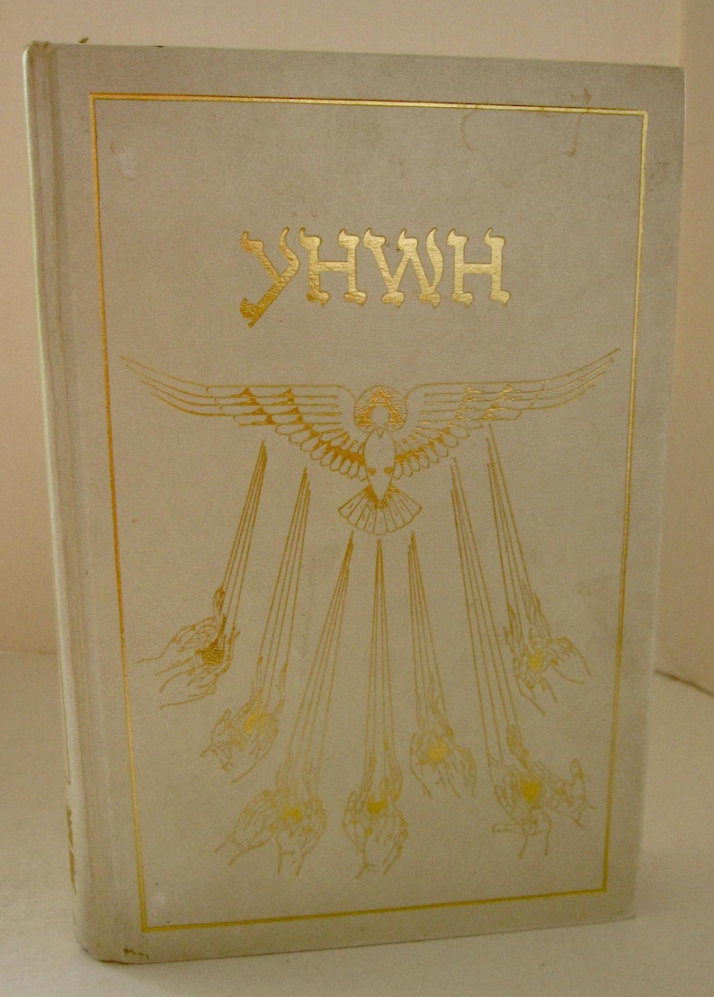 Peut inclure: Livre vintage &agrave; couverture cr&egrave;me avec lettrage et illustrations dor&eacute;s. La couverture pr&eacute;sente les lettres h&eacute;bra&iuml;ques YHWH et une illustration d&eacute;taill&eacute;e d'une colombe aux ailes d&eacute;ploy&eacute;es et des rayons &eacute;manant de celle-ci.