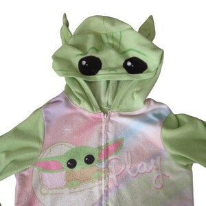 May include: Green hooded zip-up onesie with a pink and blue tie-dye pattern. The hood has a green alien face with large black eyes. The onesie has the word "Play" written on the front.