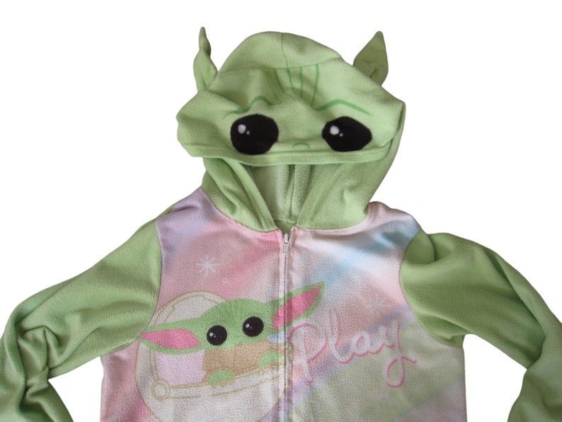 May include: Green hooded zip-up onesie with a pink and blue tie-dye pattern. The hood has a green alien face with large black eyes. The onesie has the word "Play" written on the front.