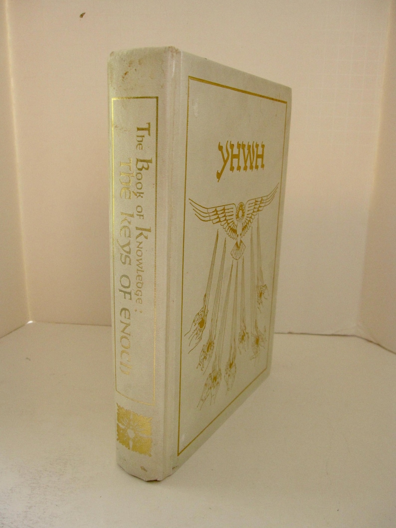 Peut inclure: Un livre &agrave; couverture rigide de couleur cr&egrave;me avec des lettres dor&eacute;es. Le titre "The Book of Knowledge: The Keys of Enoch" est imprim&eacute; sur le dos. La couverture avant pr&eacute;sente le mot "YHWH" et une illustration d'aigle avec des rayons.