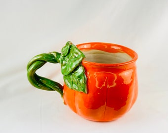 May include: Orange ceramic pumpkin mug with a green leafy handle.