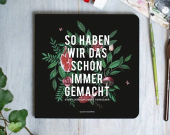 Puede incluir: Un libro negro con el título "So haben wir das schon immer gemacht" y el subtítulo "Ein Bilderbuch über Tiersessen" de Carolin Günthner. La portada presenta una ilustración estilizada de un corazón, hojas y flores.