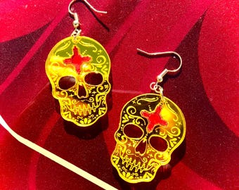 May include: A pair of yellow and red skull earrings with intricate floral designs. The earrings are made of acrylic and have a shiny finish.