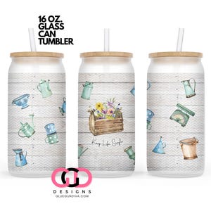 May include: A white 16 oz. glass can tumbler with a wooden lid and a straw. The tumbler features a watercolor design of gardening tools, flowers, and the text "Keep Life Simple".