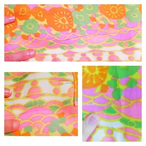 May include: Close-up of a colorful fabric with a repeating pattern of flowers and geometric shapes in shades of pink, orange, green, and yellow.