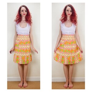 May include: A pink and orange floral print skirt with a white top and a white polka dot pattern. The skirt has a high waist and a ruffled hem.