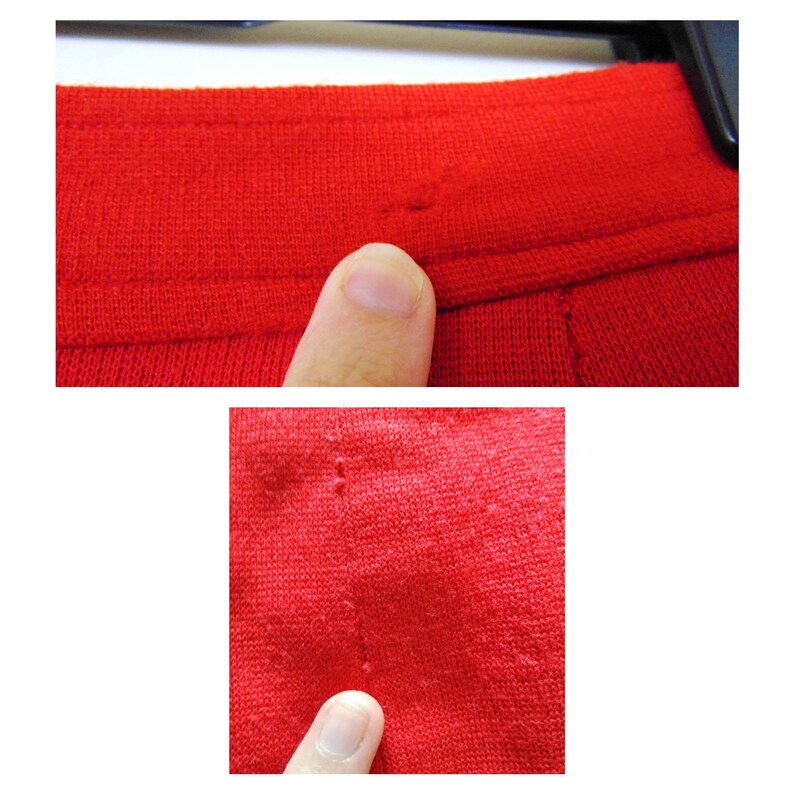 May include: Close-up of a red knitted fabric with visible stitching and small holes. The fabric is textured and has a soft appearance.