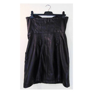 May include: A black strapless dress made of faux leather. The dress has a fitted bodice and a slightly flared skirt.